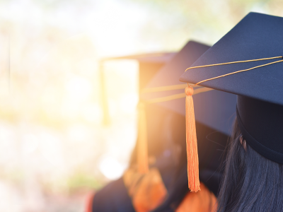 Image of graduates from the back, showing their graduation hats and tassels