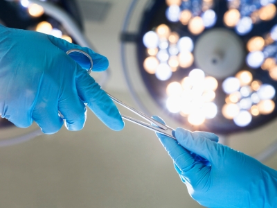 Image of gloved hands passing a surgical instrument