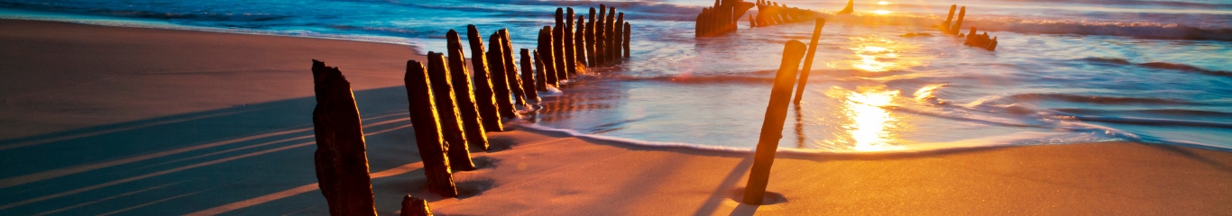 Beach at sunrise with remain of shipwreck visible at left