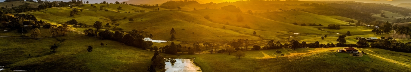 Image of sunrise over rolling green hills and a lake